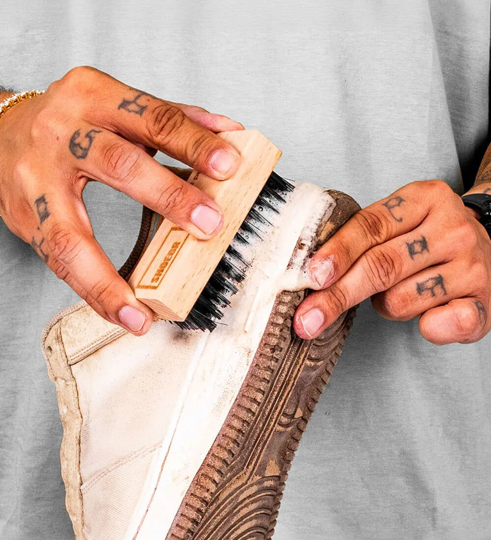 Person cleaning a shoe midsole with the SHOEGR All-Purpose Shoe Brush 