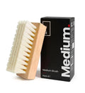 SHOEGR Medium brush with wooden handle and white PP bristles next to its packaging on a white background